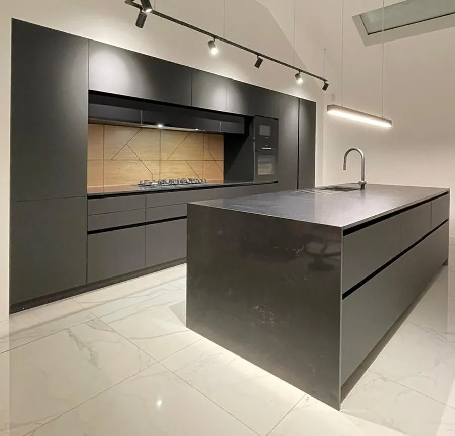 Anthracite handleless kitchen with a stone-effect waterfall island, timber-effect splashback and track lighting