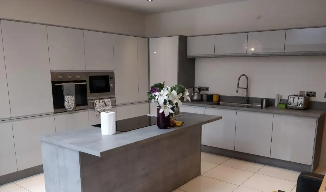 Light grey gloss handleless kitchen with a concrete-effect island
