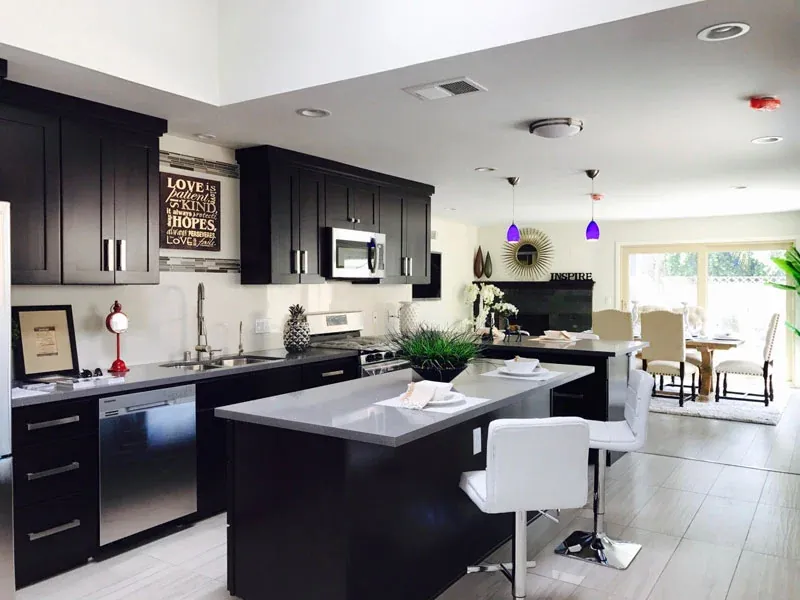 Ebony shaker cabinets with a grey worktop island and white bar stools