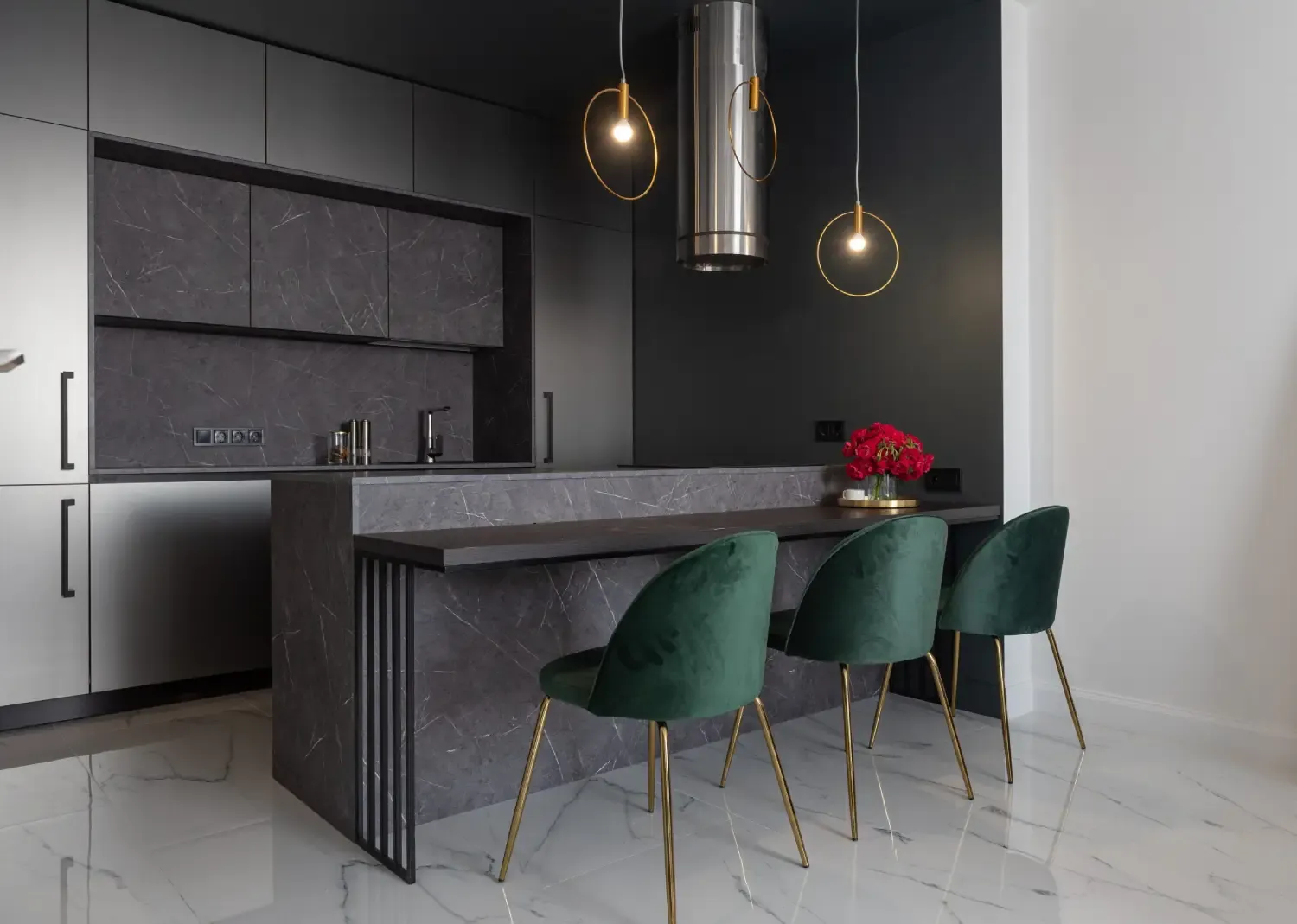 Anthracite and light grey kitchen with bar handles, a grey marble-effect breakfast bar, green velvet chairs and brass ring pendants
