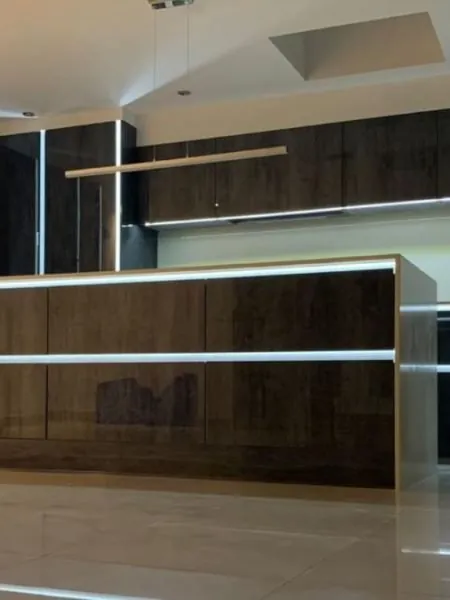 Dark woodgrain island and wall units with LED strips in the handle rails and a linear timber pendant light