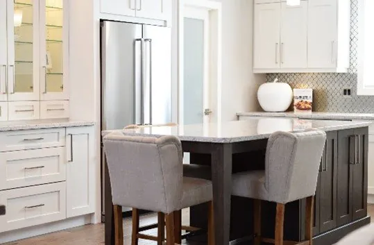 White shaker cabinets with a dark shaker island, speckled granite worktop and upholstered stools