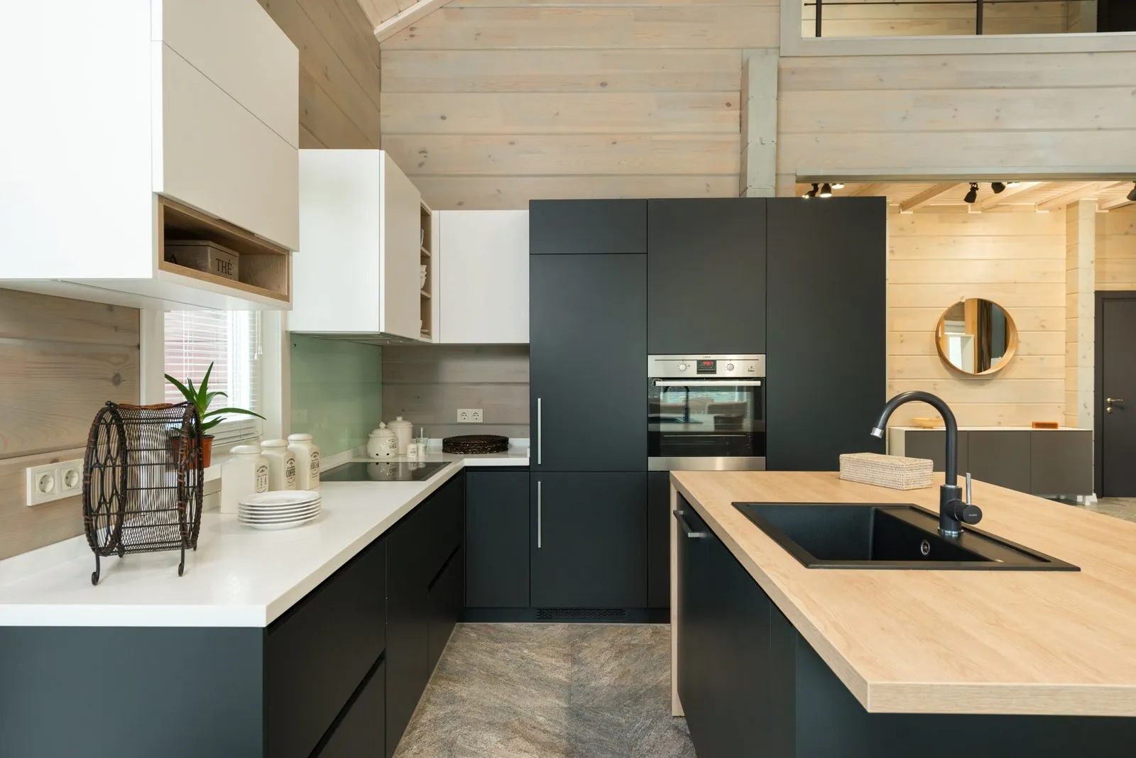 Dark green-black matt base units, white wall units and an island with an oak worktop